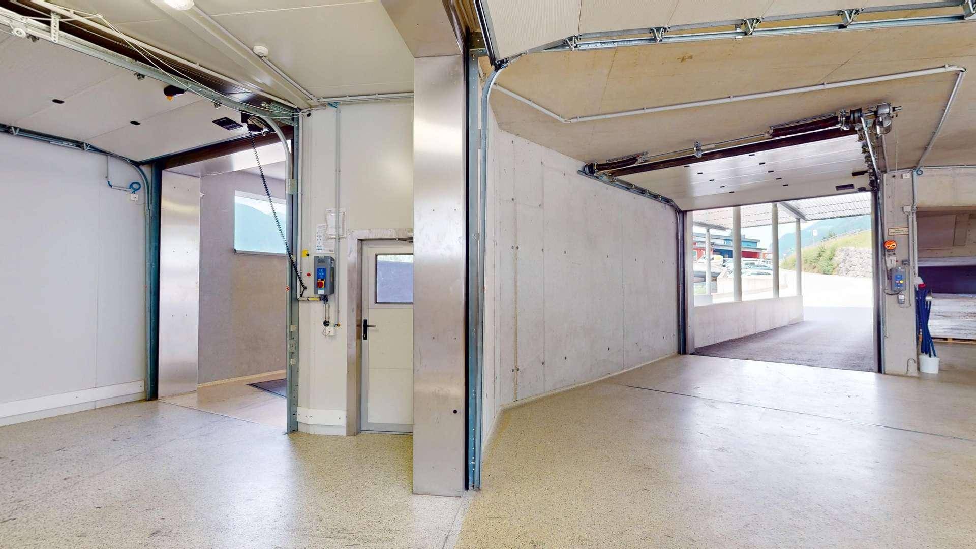 Heller Garagenbereich mit mehreren Rolltoren, Betonelementen und Zugangstüren.