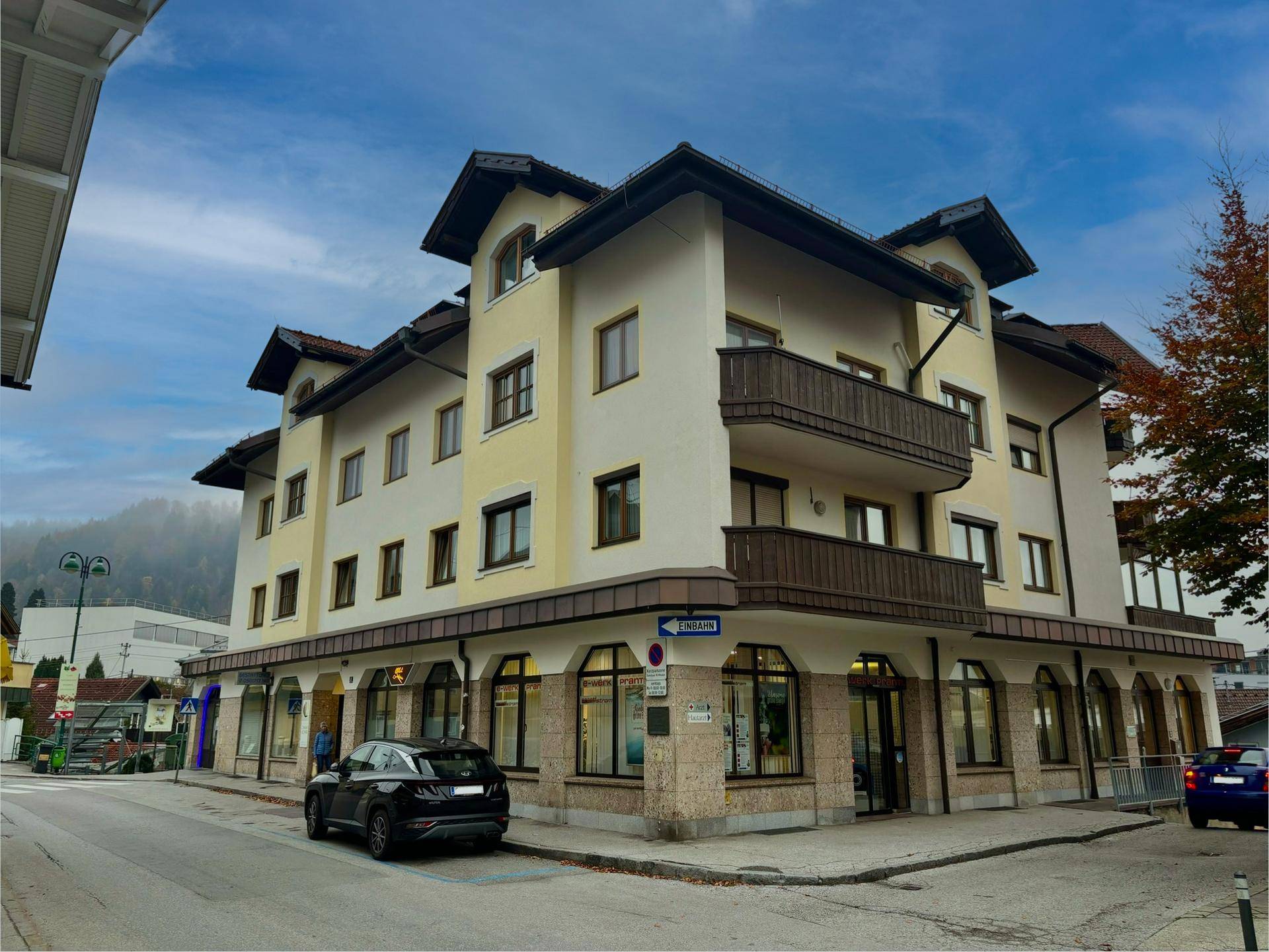 Mehrstöckiges Gebäude mit Geschäften im Erdgeschoss und Wohnungen darüber, in traditioneller Architektur mit Balkonen.