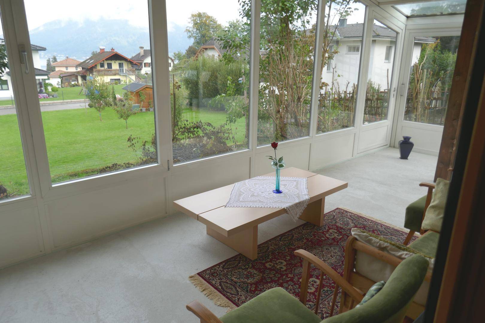 Heller Wintergarten mit großen Fenstern, die einen schönen Blick auf den Garten und die Umgebung bieten.