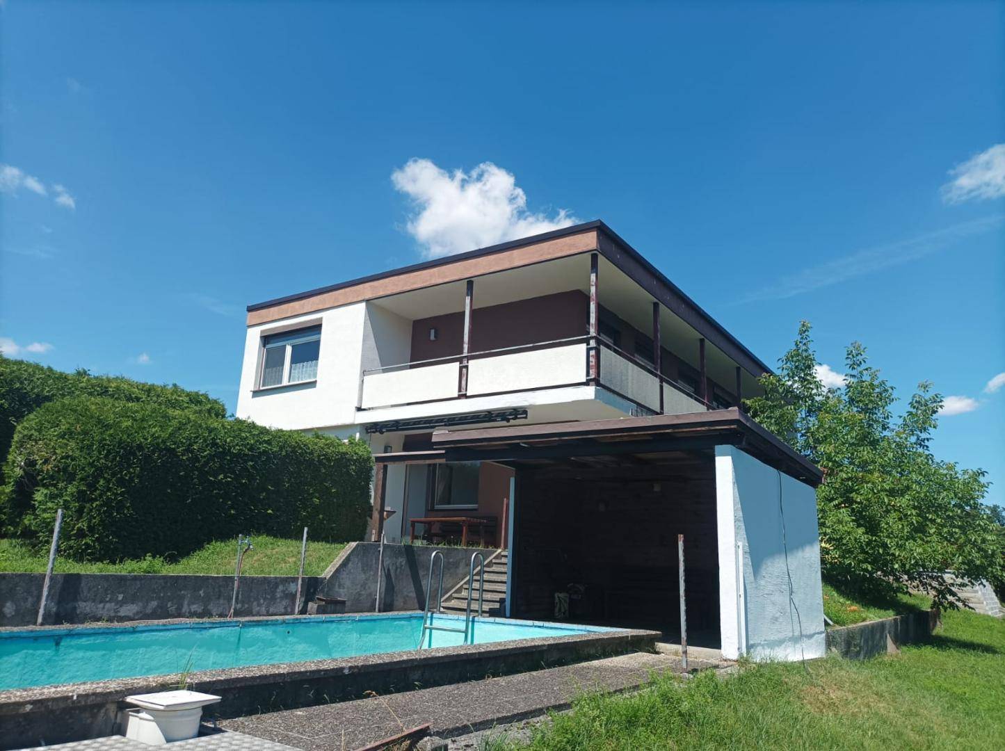 Seitenansicht des Hauses mit Außenpool, Carport und Blick auf die umliegende Landschaft.