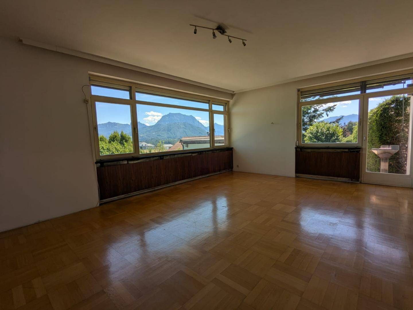 Großes, helles Wohnzimmer mit Parkettboden und weitem Blick auf die Berge.