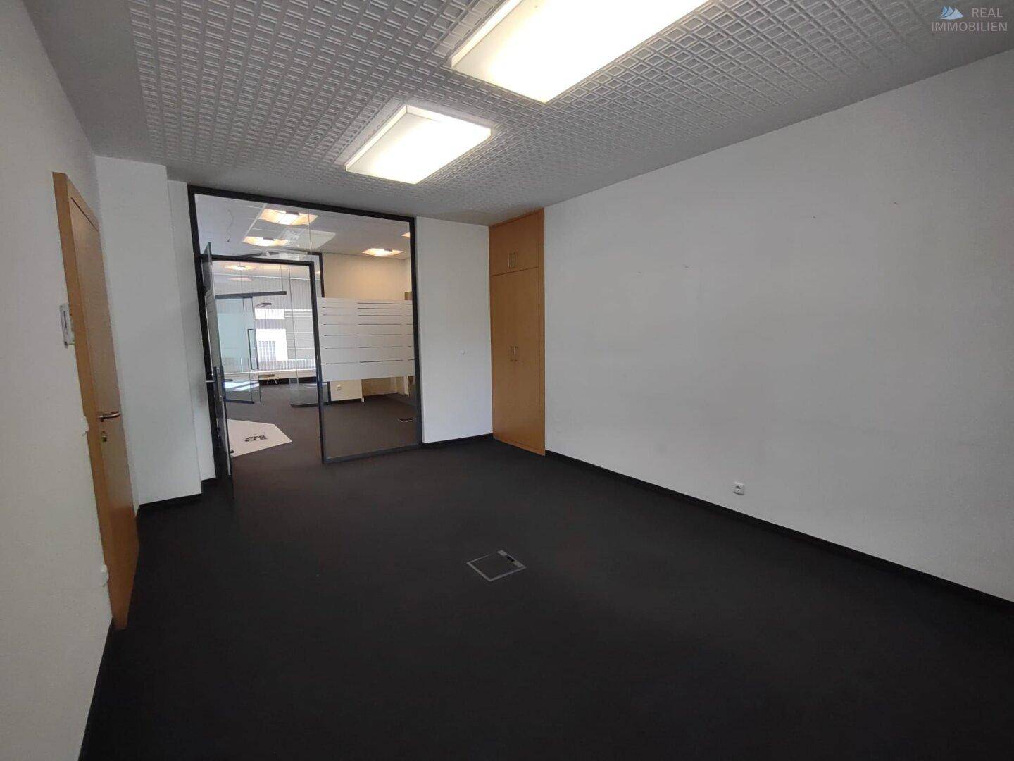 Separater Büroraum mit Teppichboden und Holztüren, ideal für konzentriertes Arbeiten.