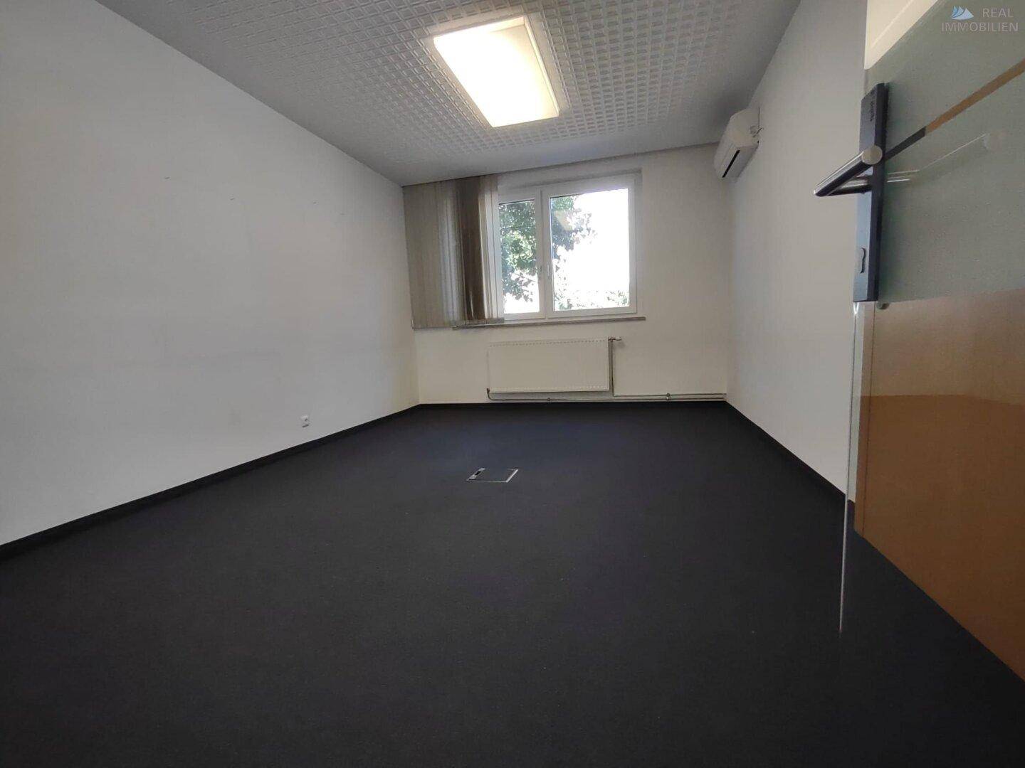 Ruhiger Büroraum mit Teppichboden, Fenster und Heizkörper, gut für Einzelbüros geeignet.