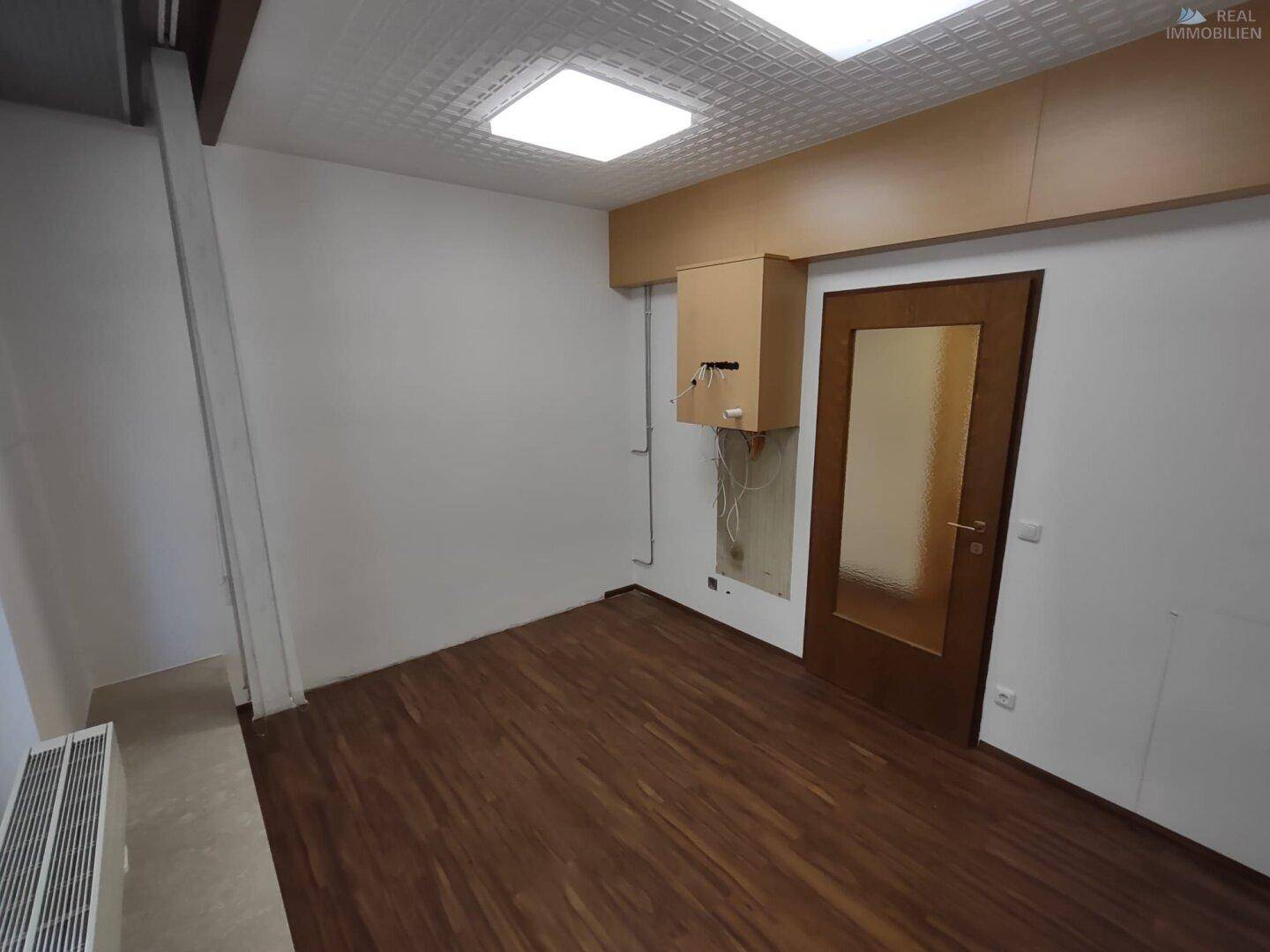 Raum mit Laminatboden und Holztür, geeignet als Büro oder Abstellraum.