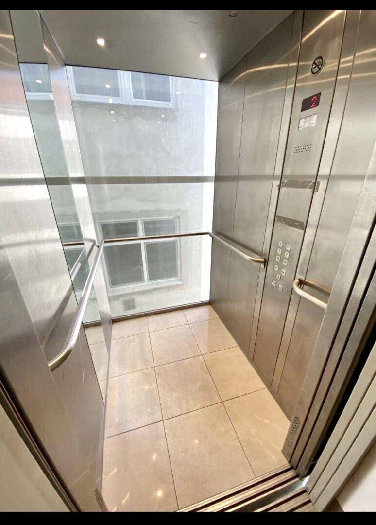 Moderner Aufzug mit Glaswänden und Edelstahlverkleidung im Gebäude.