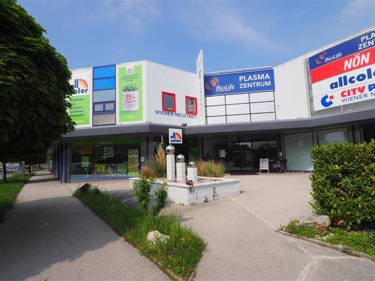 Weitläufige Außenansicht eines Geschäftskomplexes mit Grünflächen und einem klaren Himmel.
