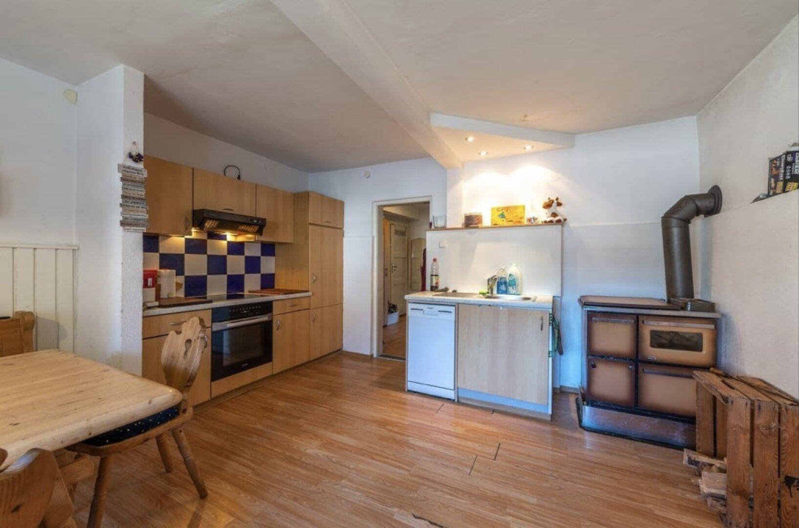 Rustikale Küche mit Holzboden, Einbauküche und traditionellem Holzofen.