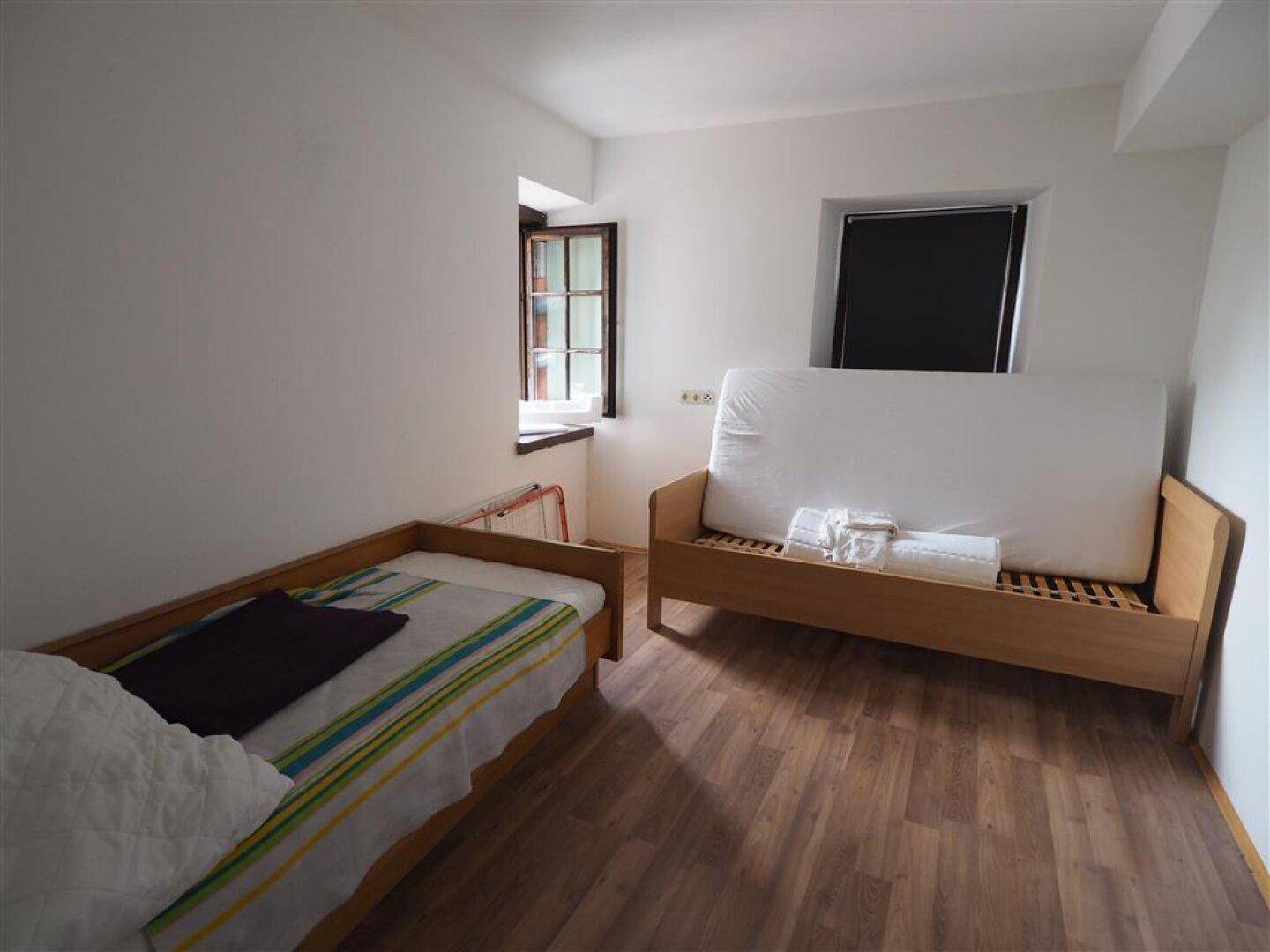 Helles Schlafzimmer mit zwei Einzelbetten und Holzboden, ideal als Gästezimmer.