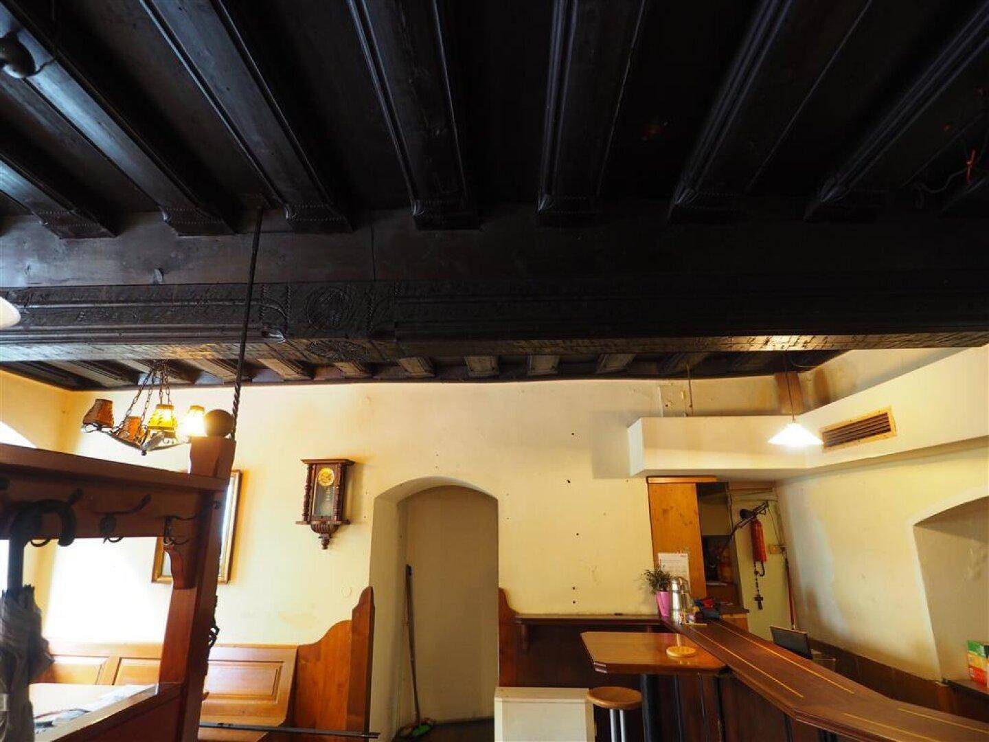 Dunkle Holzbalkendecke über einem traditionellen Essbereich mit rustikalem Charme.