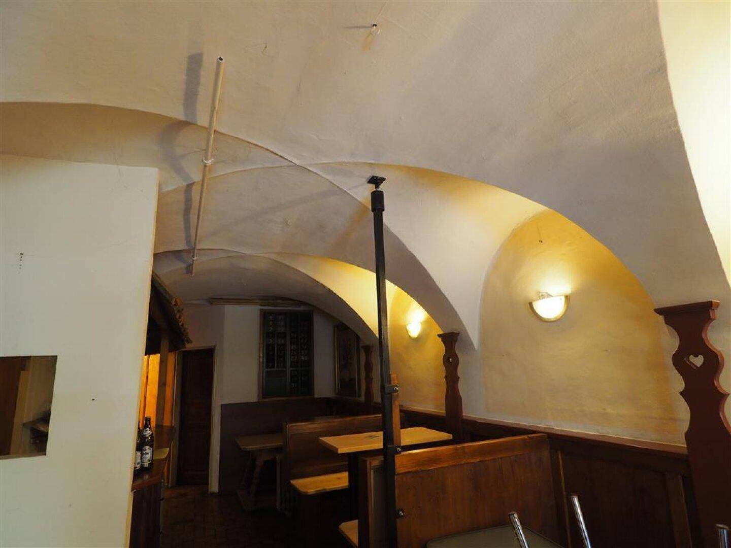 Gewölbekeller mit traditionellen Holzbänken und indirekter Beleuchtung, schafft eine rustikale Atmosphäre.