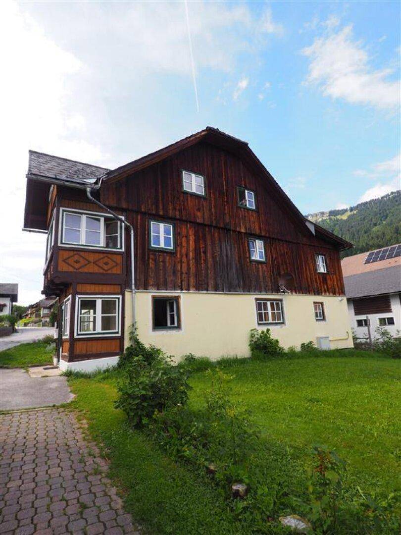 Rückseite eines Holzhauses mit großer Rasenfläche und Blick auf die umliegende Landschaft.