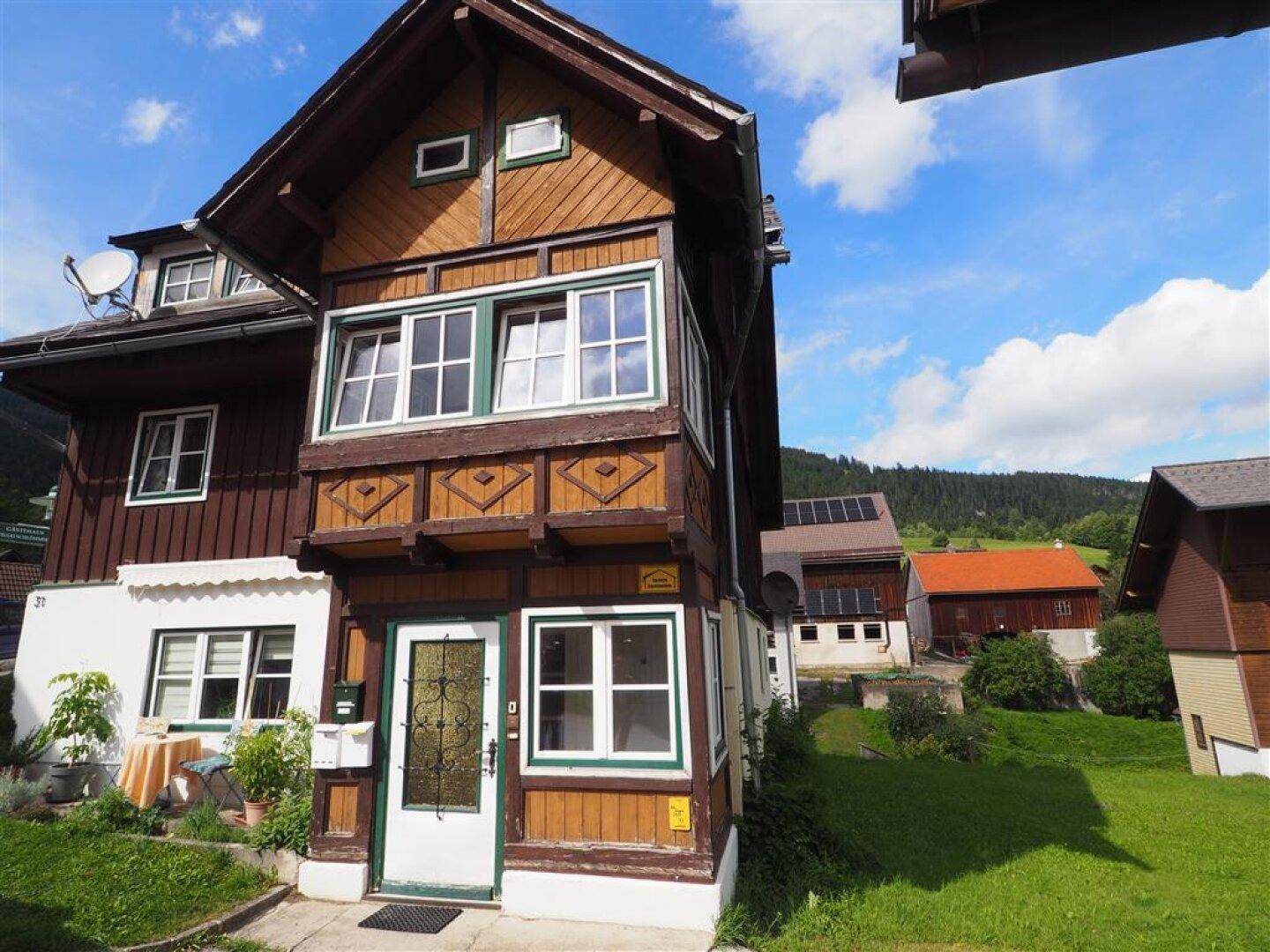 Traditionelles Holzhaus mit Balkonen und einem gepflegten Vorgarten in ländlicher Umgebung.