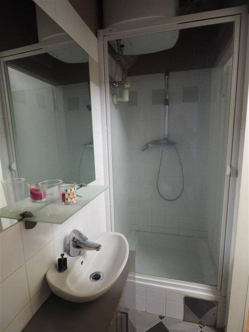 Modernes Badezimmer mit Duschkabine, Waschbecken und Spiegel, ausgestattet mit weißen Fliesen.
