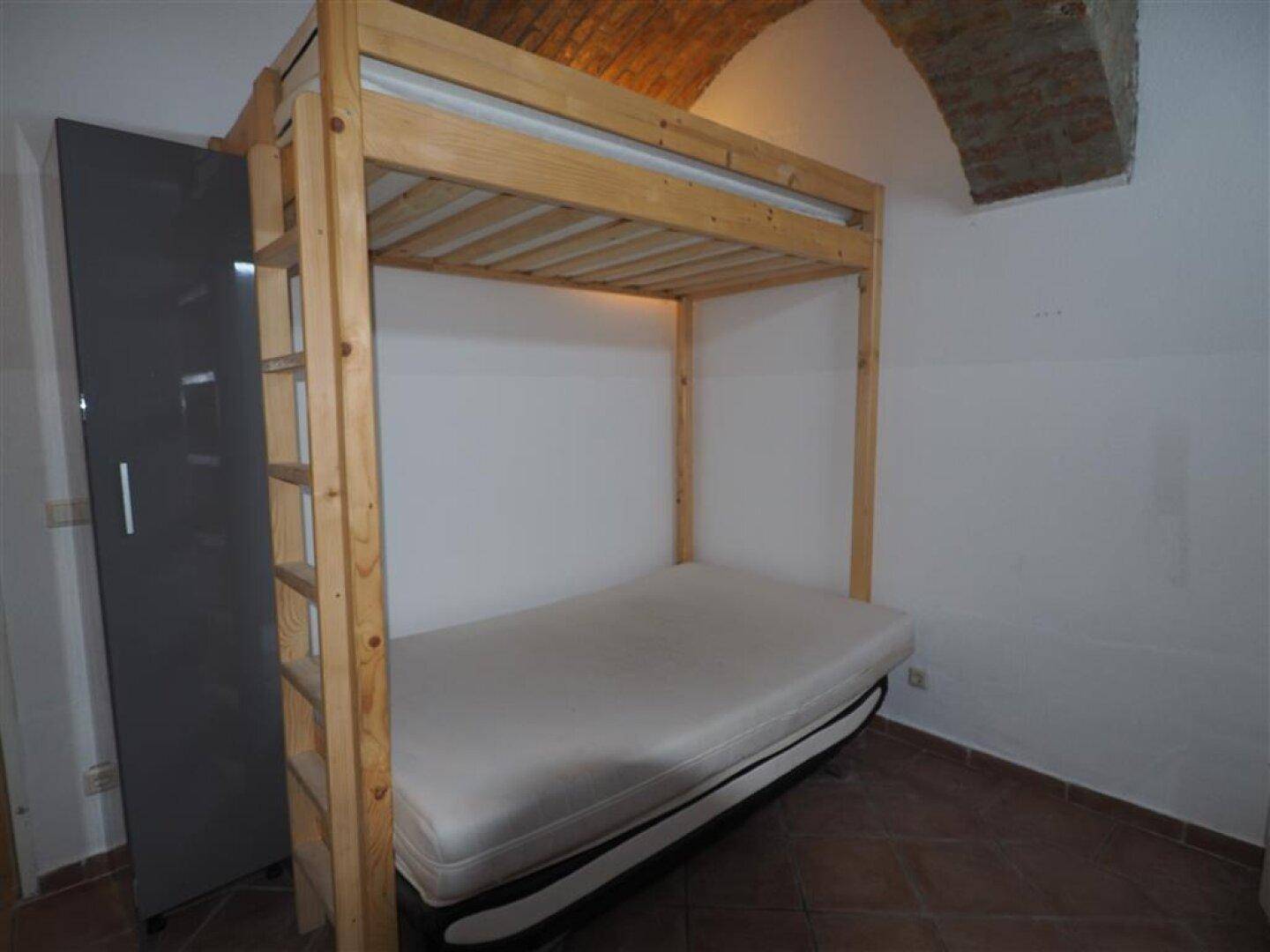 Etagenbett in einem Schlafzimmer mit Terrakottaboden und einem Kleiderschrank, unter einer Ziegelgewölbedecke.
