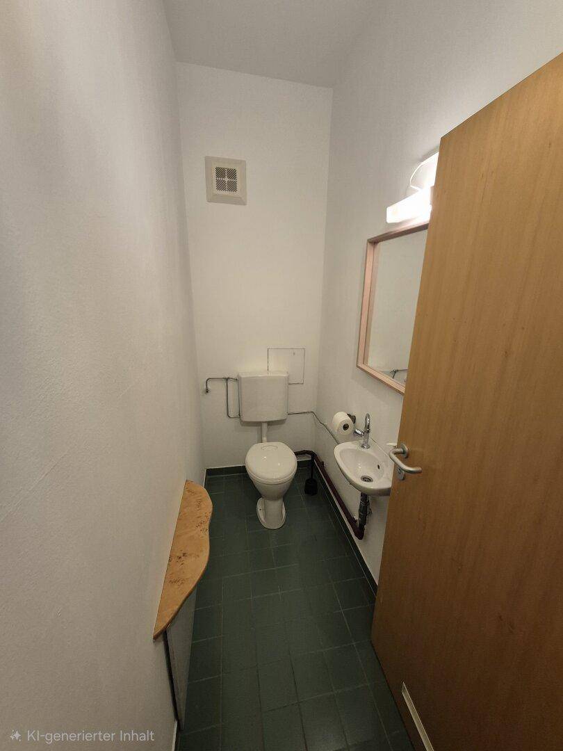 Kleines Gäste-WC mit Fliesenboden, Toilette, Waschbecken und Lüftung.