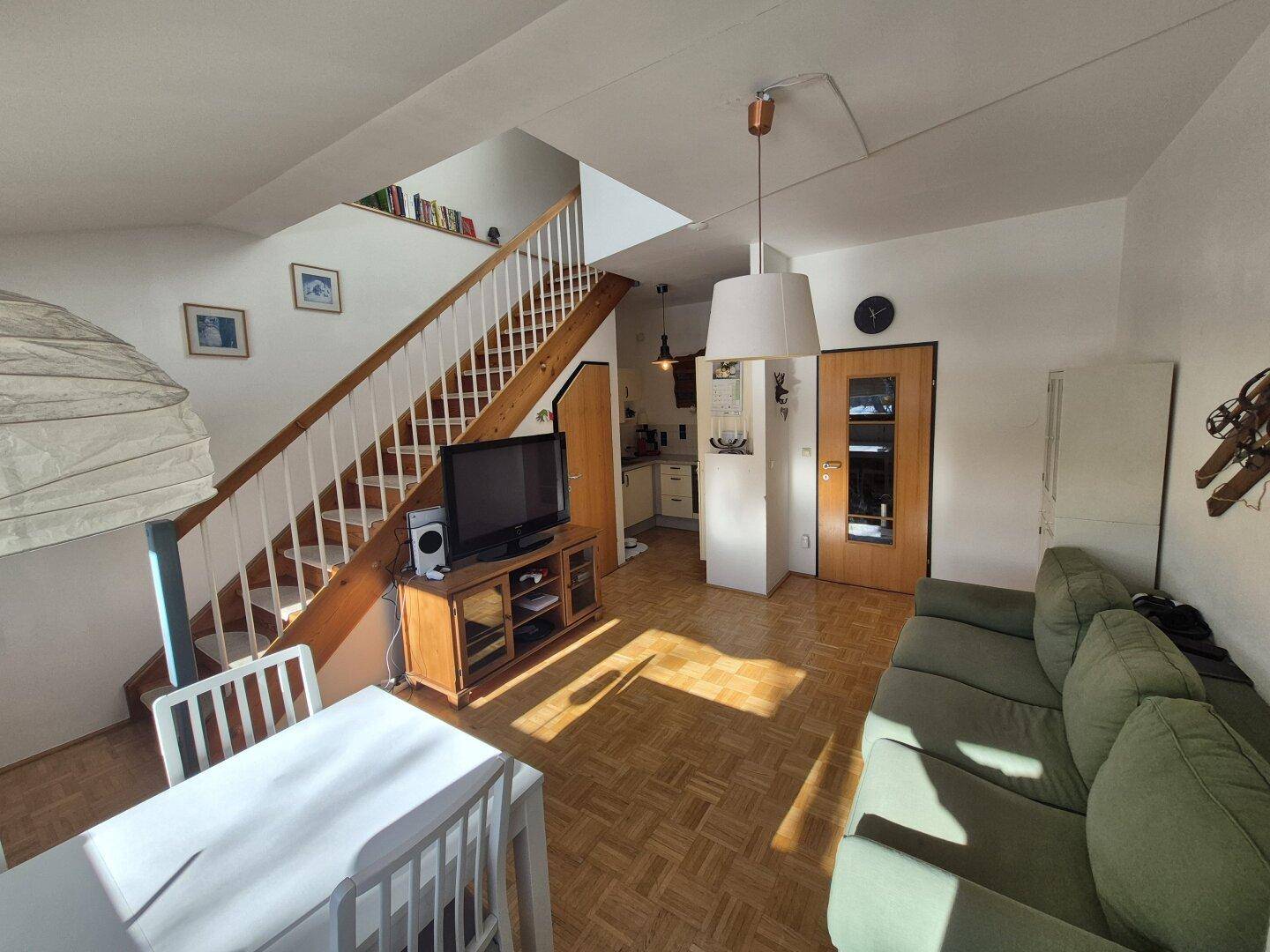 Offener Wohnbereich mit Treppe, gemütlichem Sofa und Zugang zur Küche.