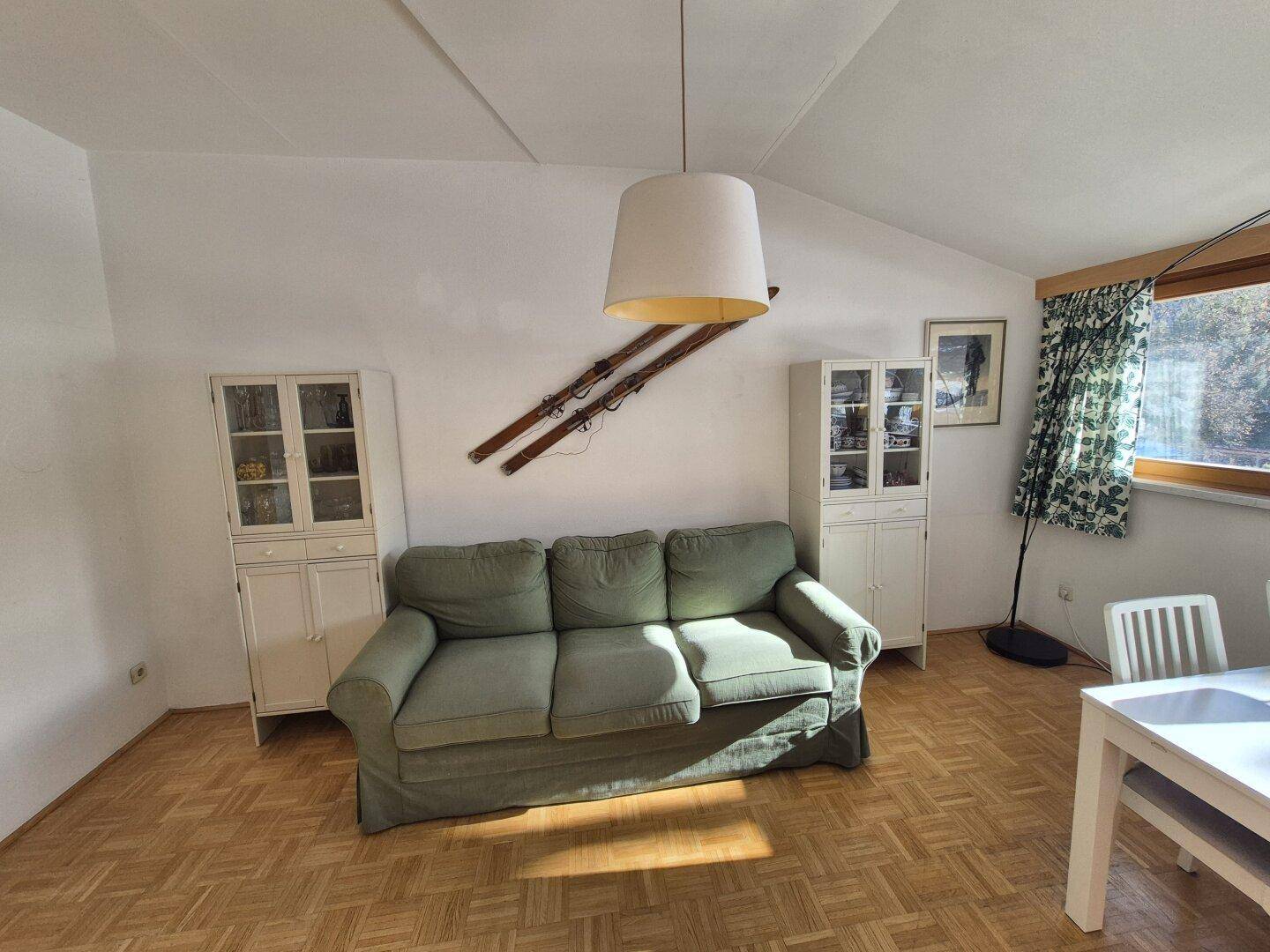 Gemütliches Wohnzimmer mit grünem Sofa, Holzboden und traditioneller Dekoration.