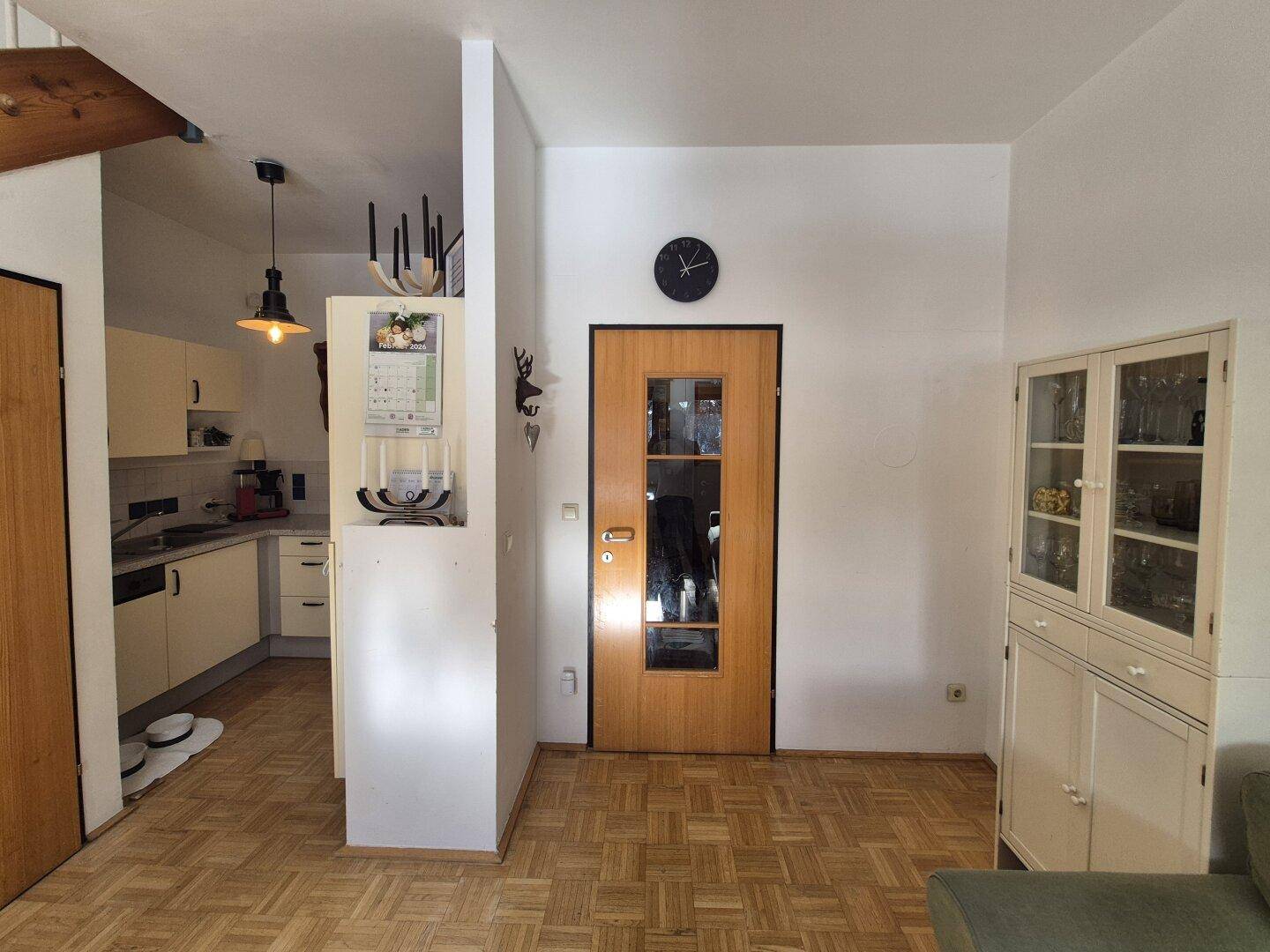 Wohnbereich mit Holzboden und offenem Übergang zu einer kompakten Küche.