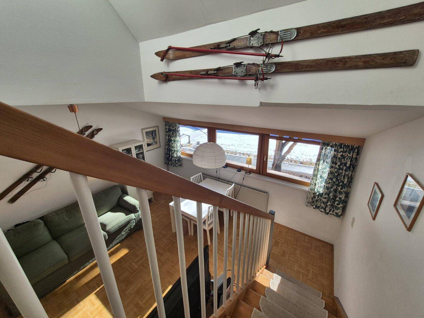 Blick von der Treppe in den offenen Wohnbereich mit Esstisch und Sofa.