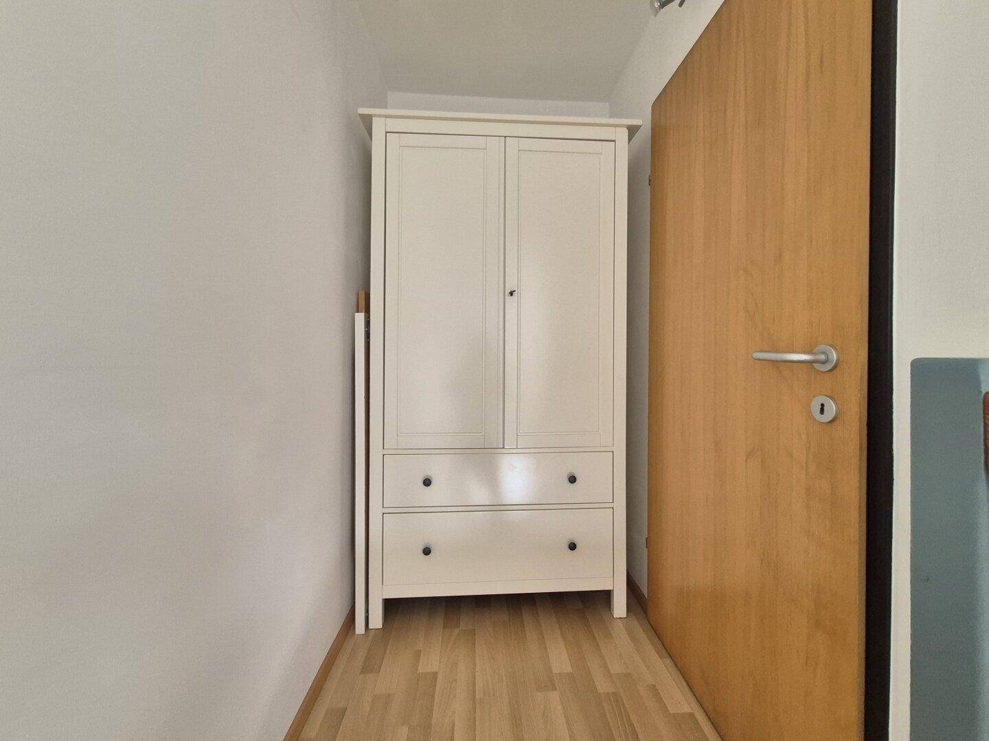 Kleiner Schrankbereich mit hellem Kleiderschrank und Holzboden.