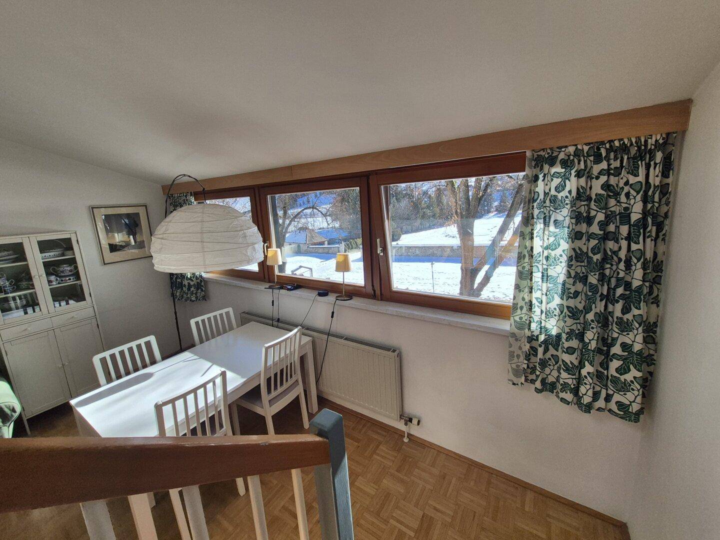 Heller Essbereich mit Holzboden und weitem Blick auf die verschneite Landschaft.