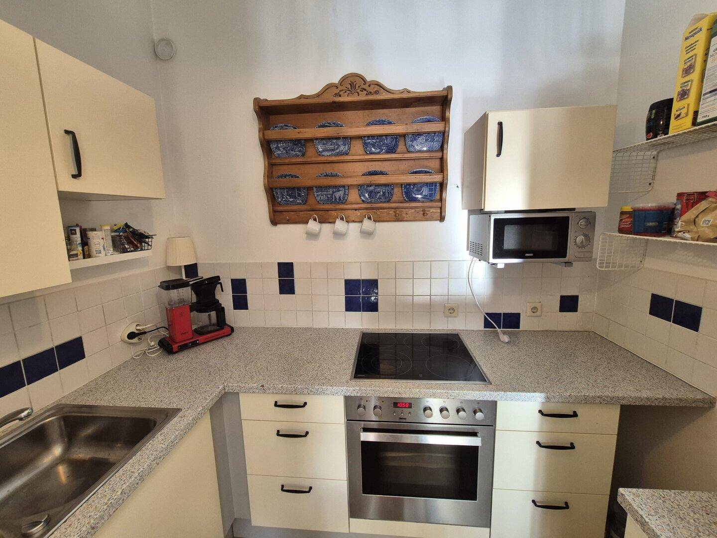 Gut ausgestattete Küche mit Kochfeld, Backofen und traditionellen blauen Fliesenakzenten.