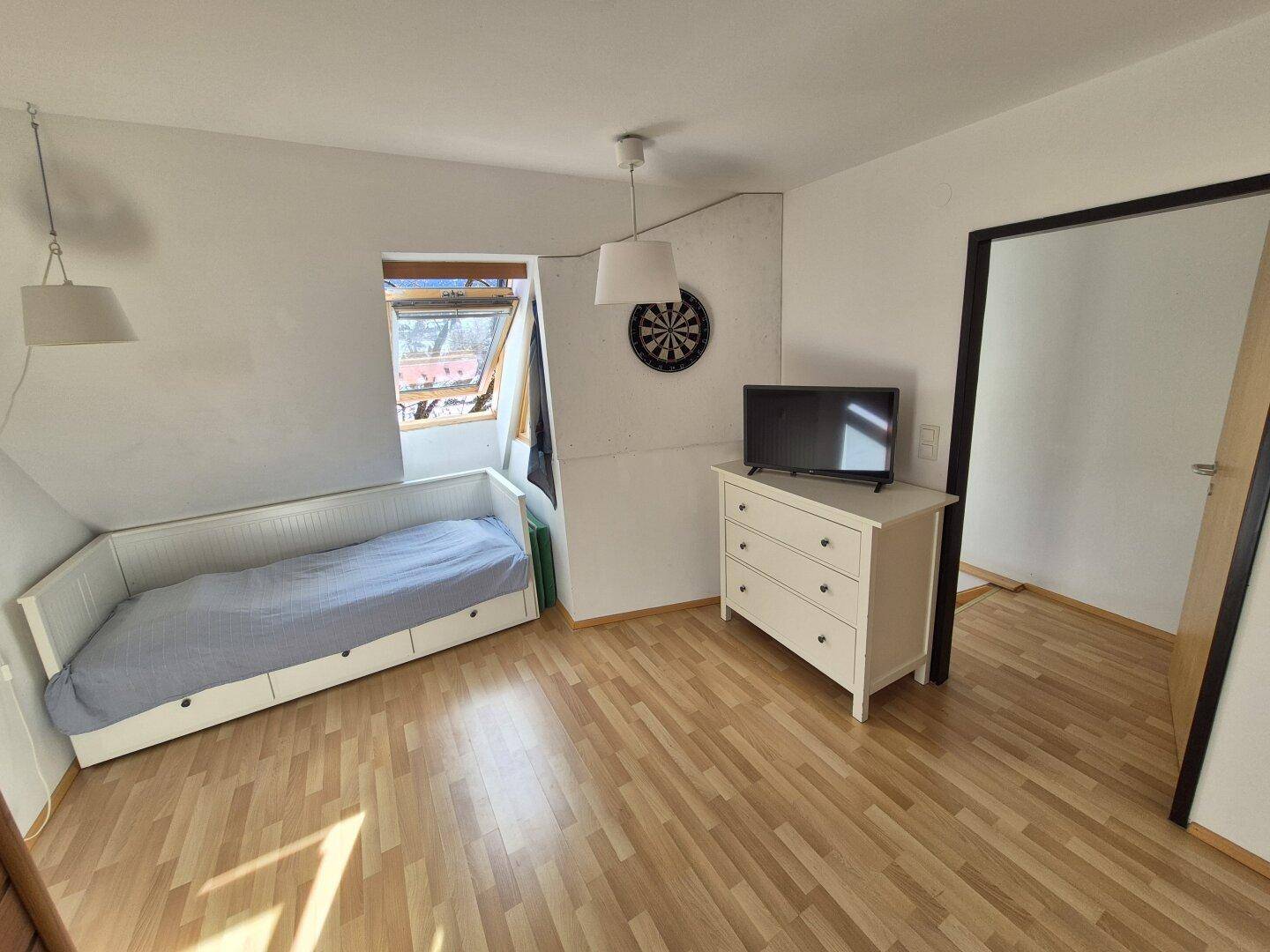 Schlafzimmer mit Sauna, Bett und Dachfenster, das viel Tageslicht hereinlässt.