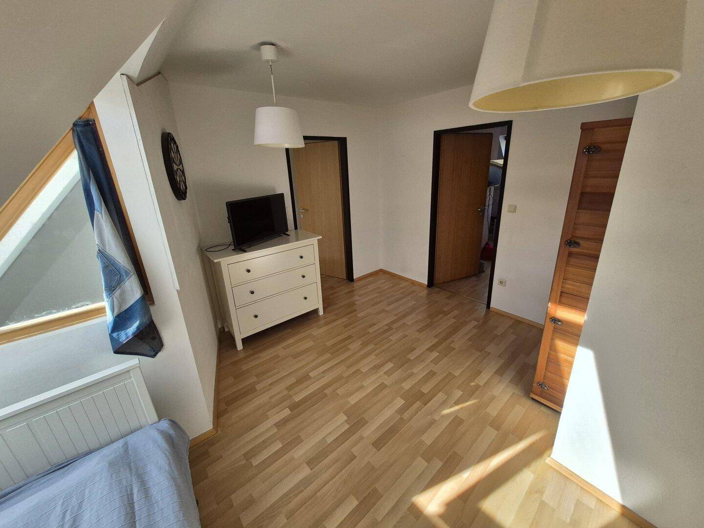 Helles Schlafzimmer mit Sauna, Bett und Dachschräge, gemütlich eingerichtet.