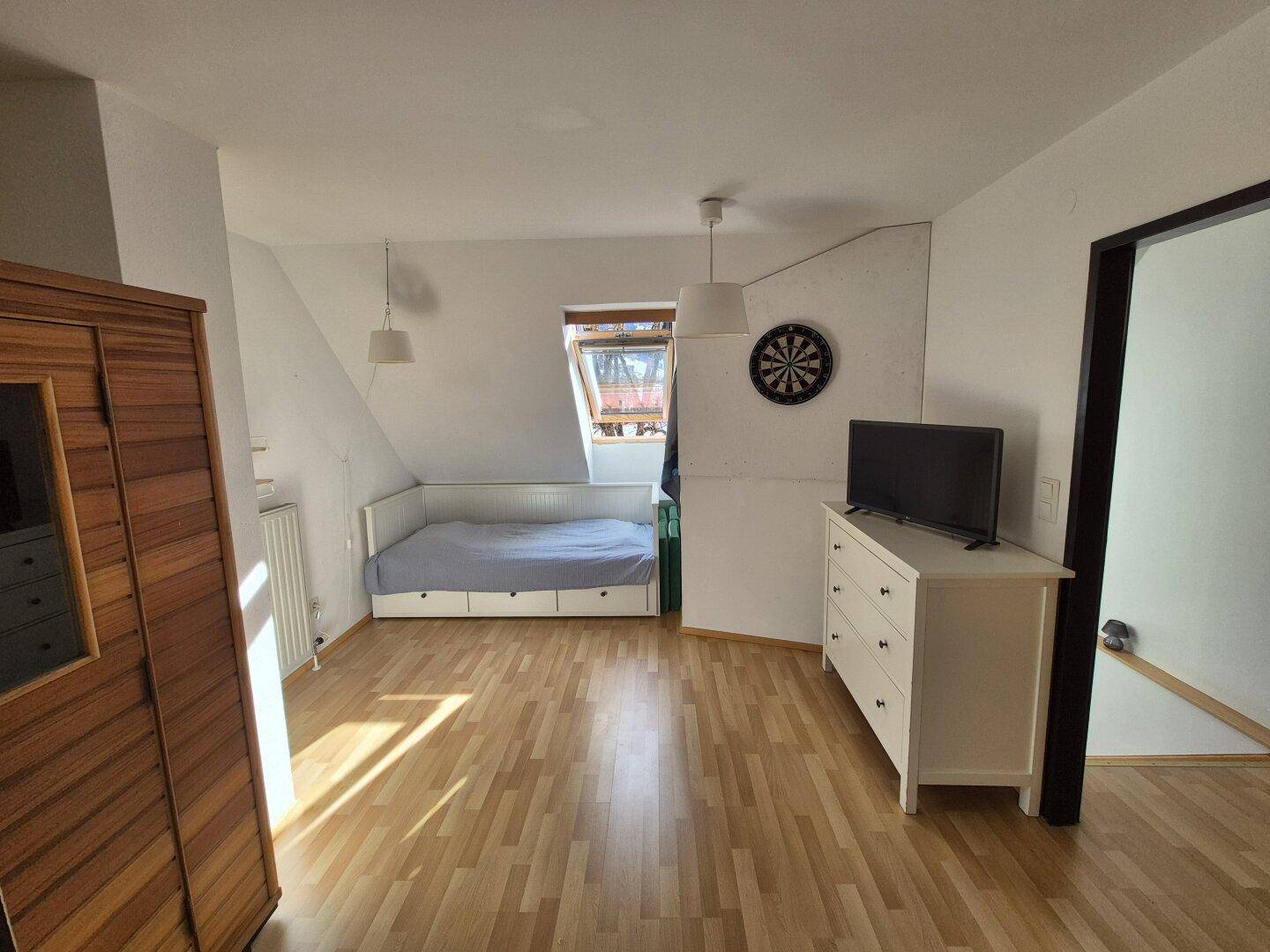 Schlafzimmer mit Holzboden, integrierter Sauna und Dachfenster für natürliches Licht.