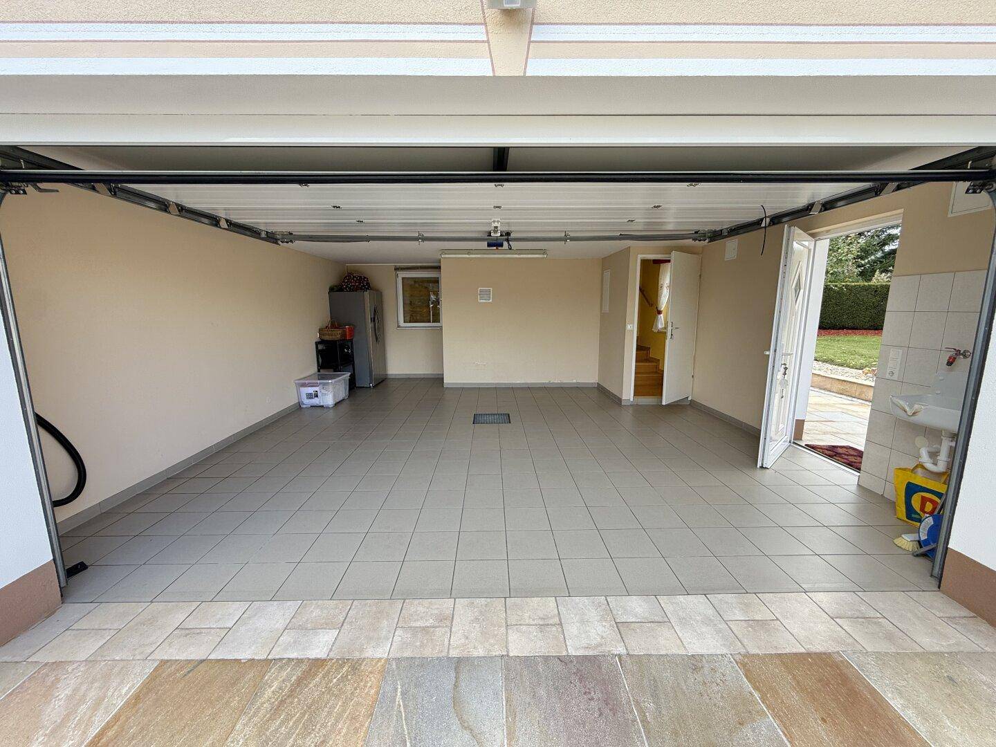 Geräumige Garage mit Fliesenboden und direktem Zugang zum Haus und Garten.