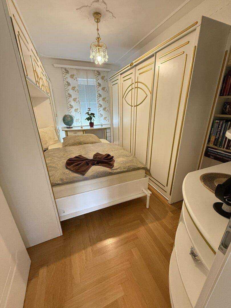 Gemütliches Schlafzimmer mit Parkettboden, Einbauschränken und Fenster.