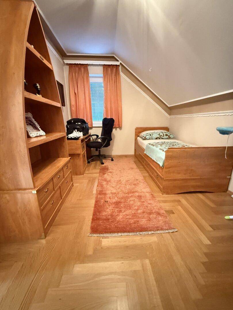 Kinderzimmer oder Arbeitszimmer mit Holzmöbeln, Parkettboden und Dachschräge.
