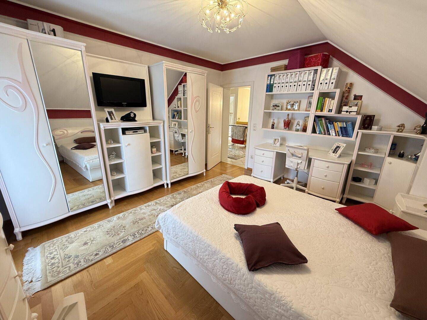 Helles Schlafzimmer mit Parkettboden, weißen Möbeln und Dachschräge.