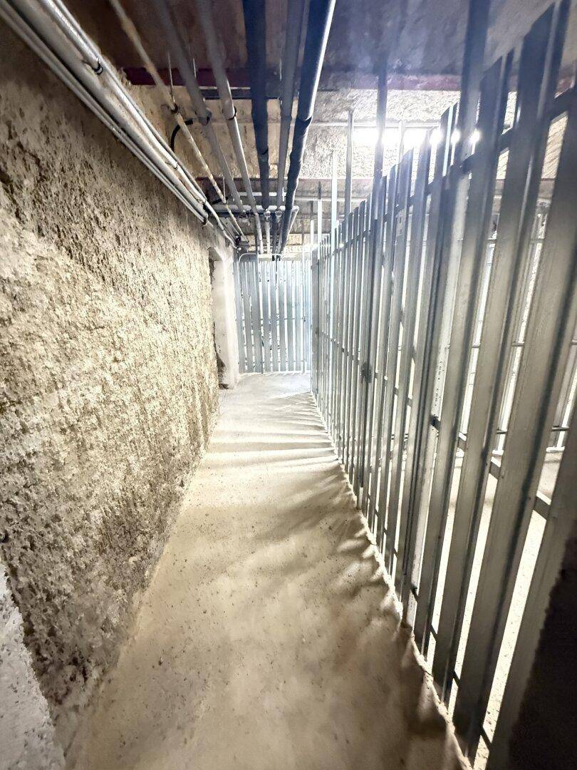 Unfertiger Kellerraum mit sichtbaren Rohren und Metallkonstruktionen.