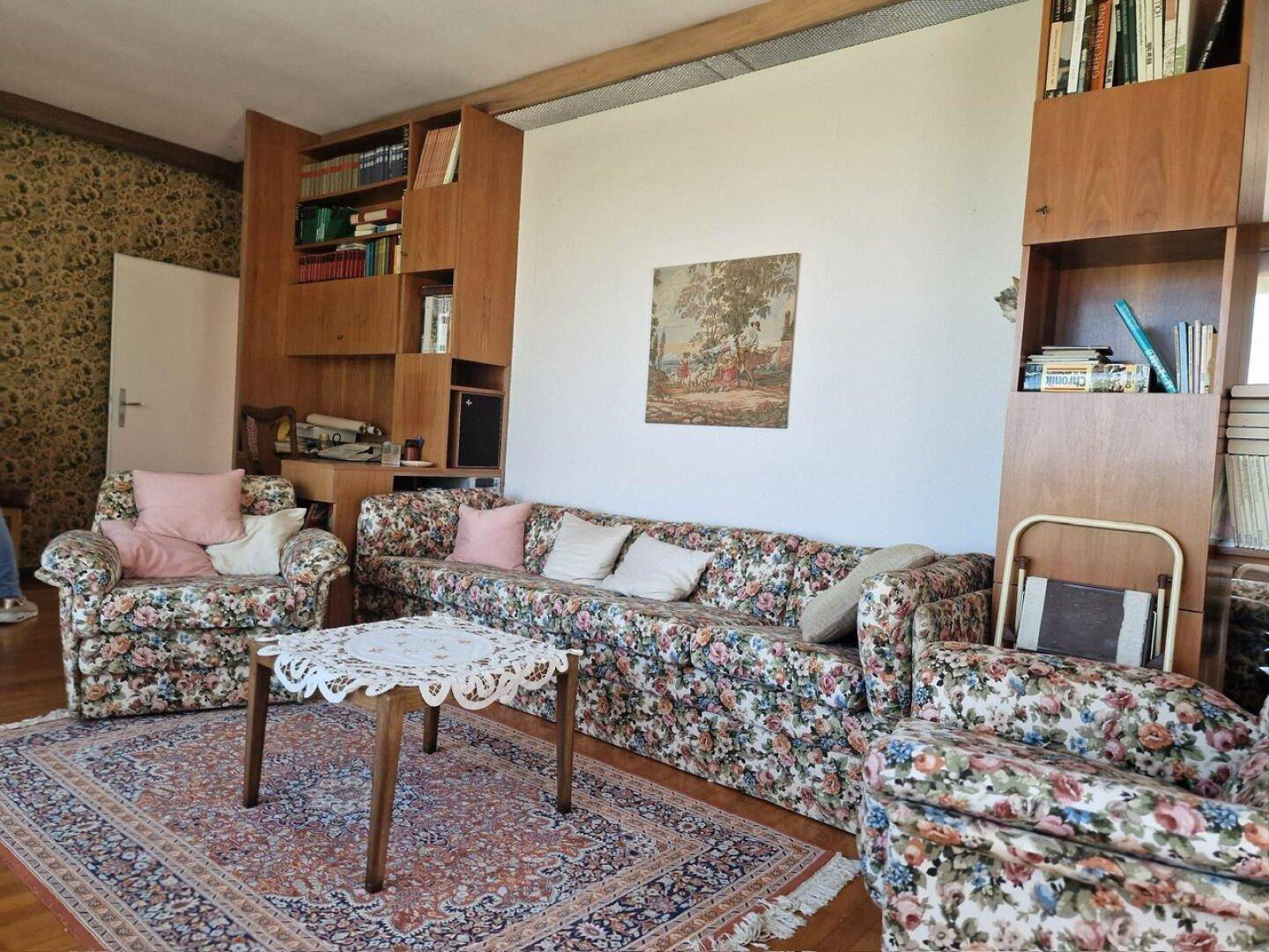 Gemütliches Wohnzimmer mit floral gemusterten Sofas, Teppich und Bücherregal, im klassischen Stil.