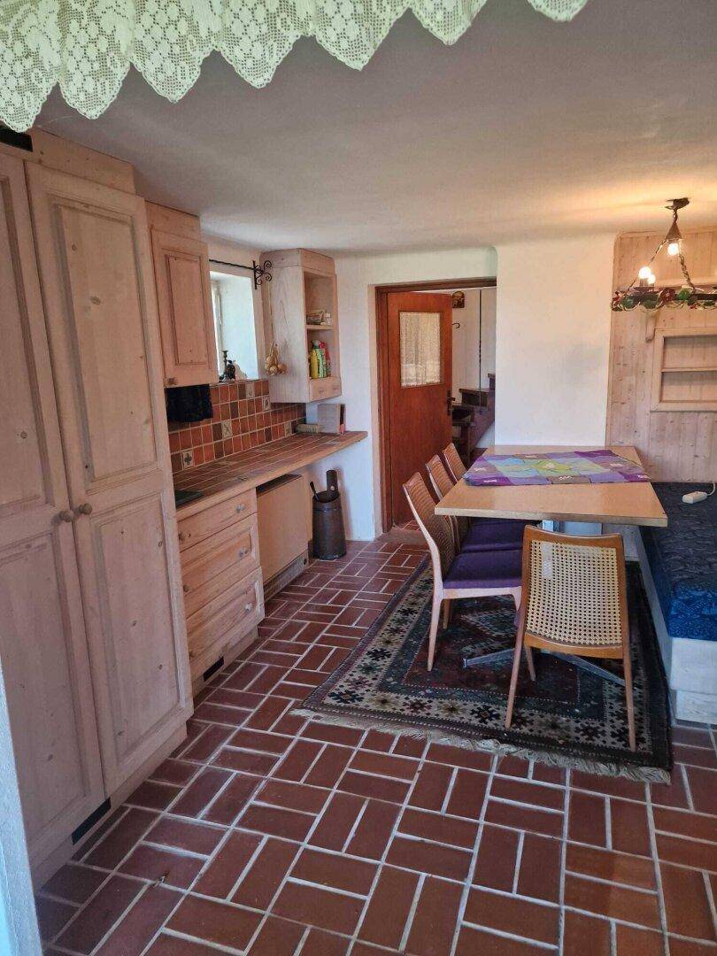 Rustikaler Essbereich mit Holztisch, Sitzbank und Terrakotta-Fliesenboden, ideal für Familienessen.