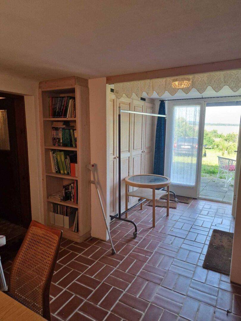 Heller Eingangsbereich mit Terrakotta-Fliesen, Bücherregal und direktem Zugang zur Terrasse.