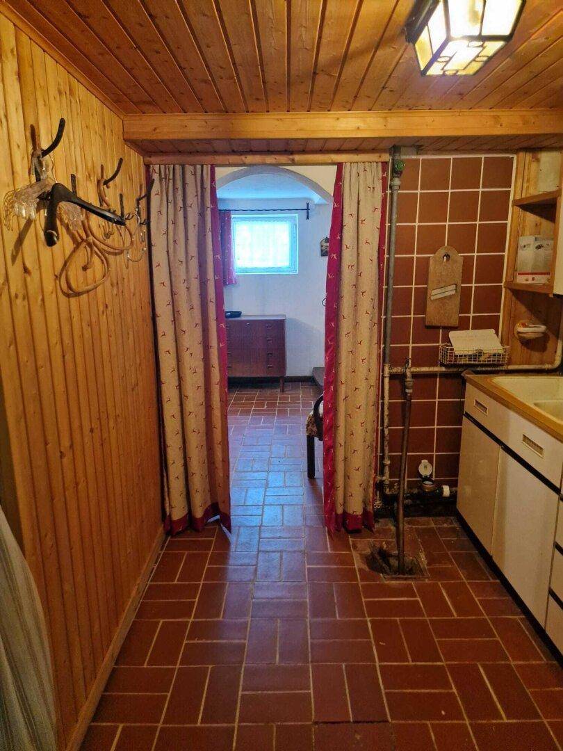 Praktischer Raum mit Holzverkleidung, Spüle und Terrakotta-Fliesenboden, ideal als Hauswirtschaftsraum.