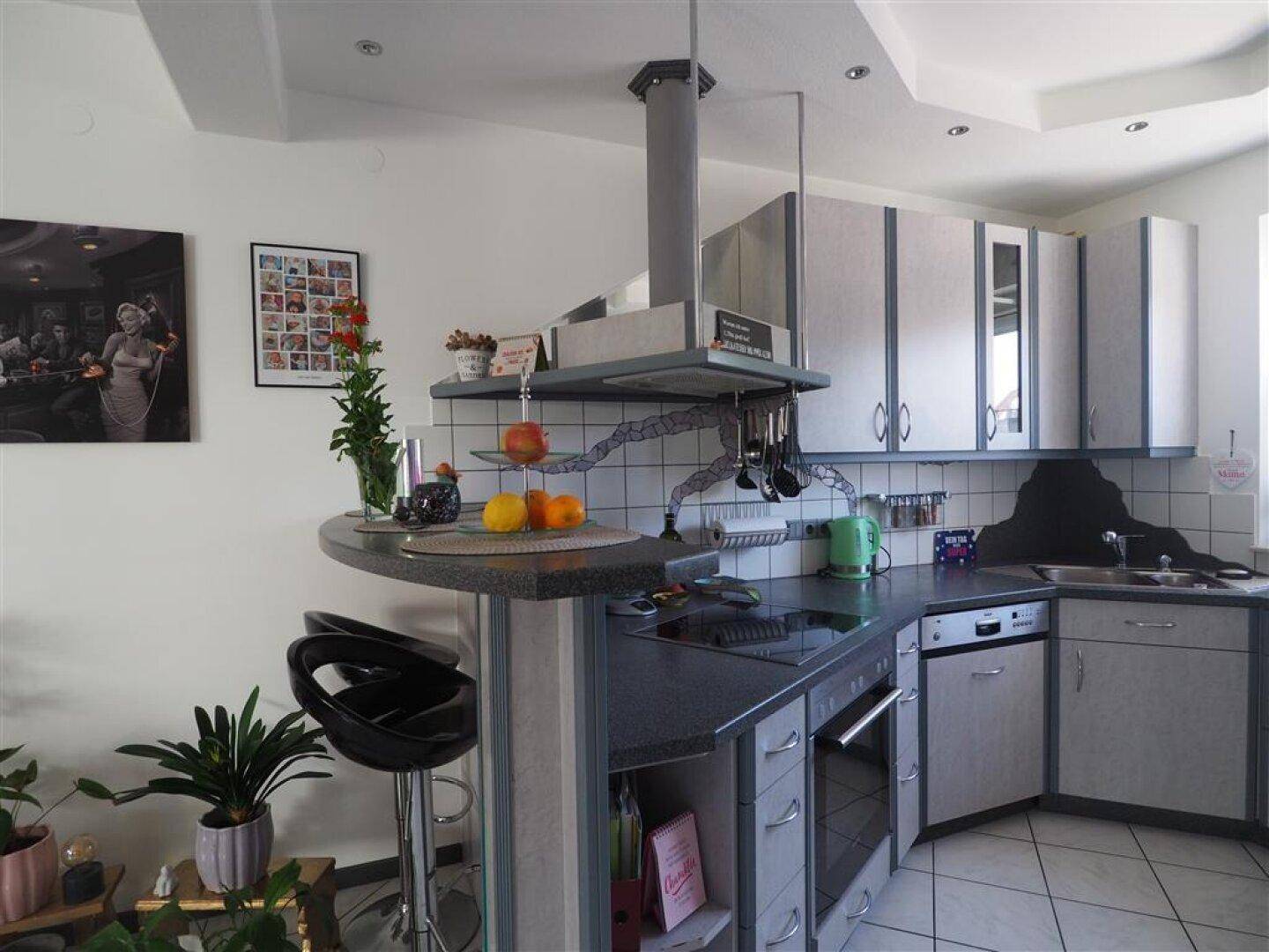 Gut ausgestattete Küche mit modernen Geräten, Frühstücksbar und Blick auf den grünen Gartenbereich.