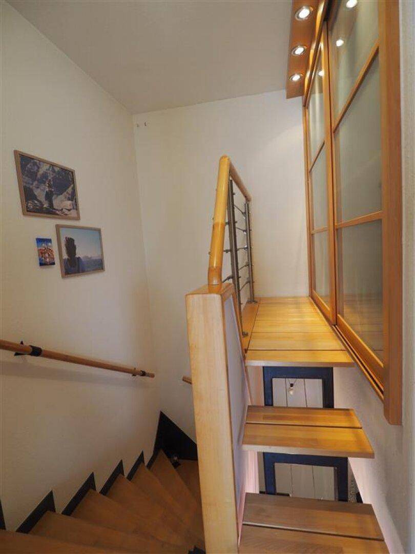 Geschwungene Holztreppe mit modernem Geländer und indirekter Beleuchtung für eine stilvolle Atmosphäre.