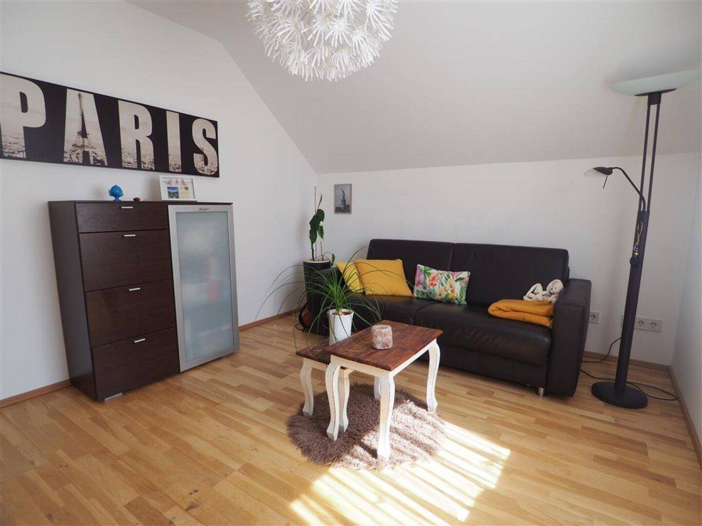 Freundliches Wohnzimmer mit Sofa, Couchtisch und Holzboden, gut beleuchtet durch Tageslicht.