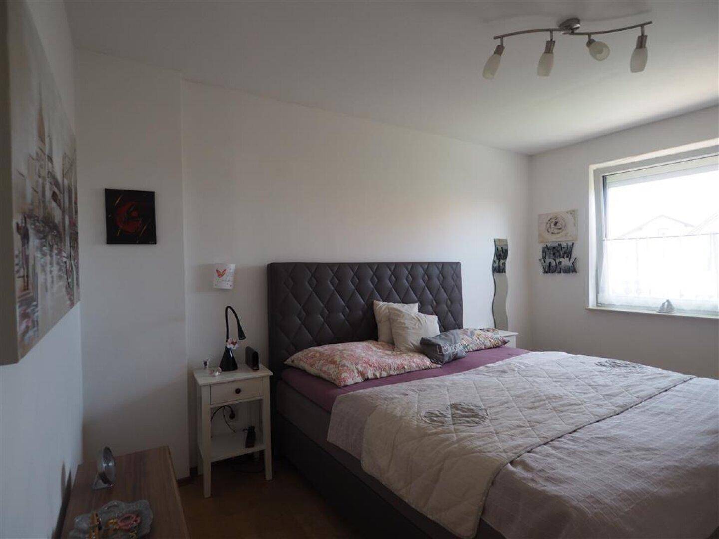 Helles Schlafzimmer mit großem Bett, Nachttischen und Fenster für natürliches Licht und Komfort.