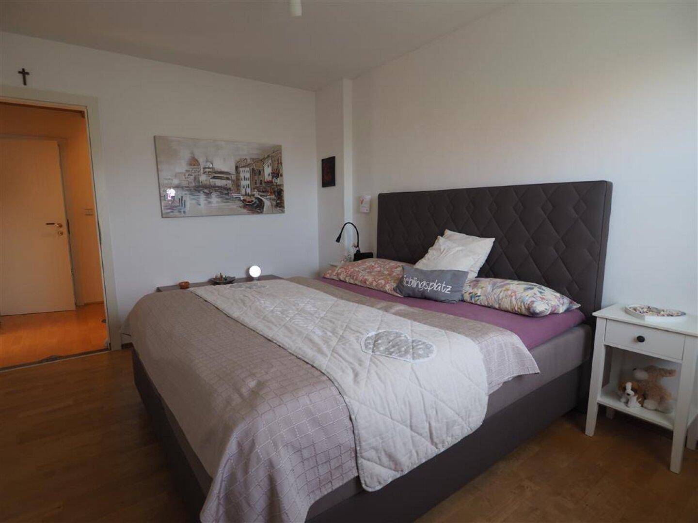 Helles Schlafzimmer mit einem großen Bett, Nachttisch und einem Gemälde an der Wand.