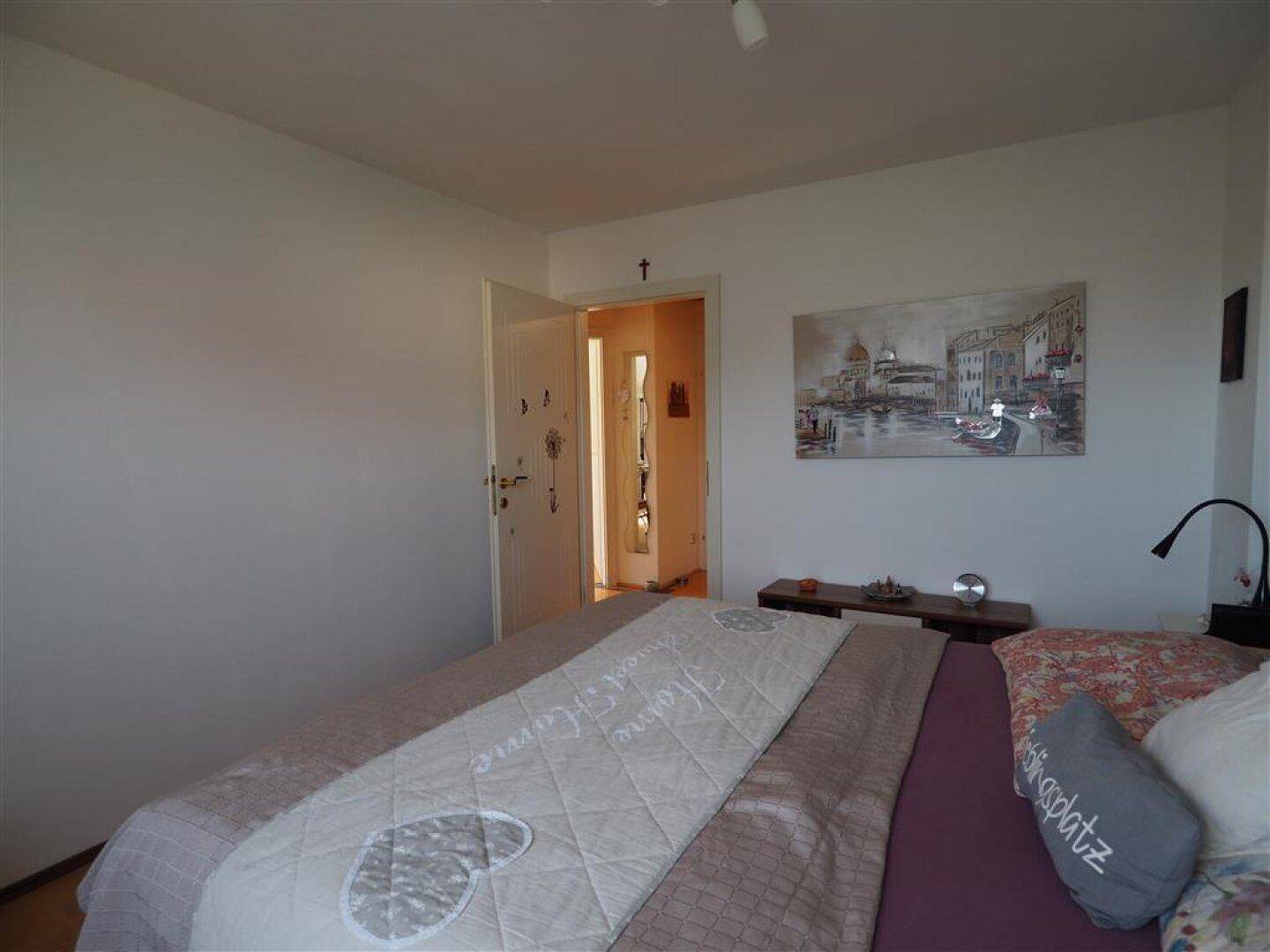 Geräumiges Schlafzimmer mit Holzboden und einer Tür, die zu einem Flur führt.