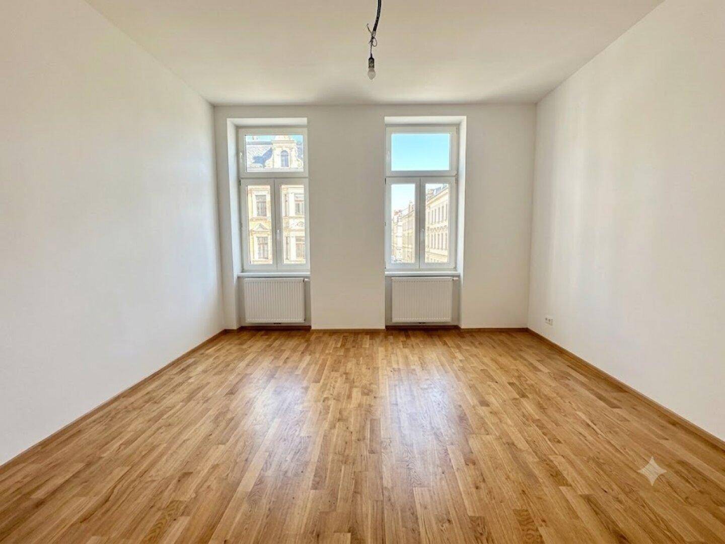 Geräumiges, helles Zimmer mit Holzboden und zwei großen Fenstern, frisch renoviert.