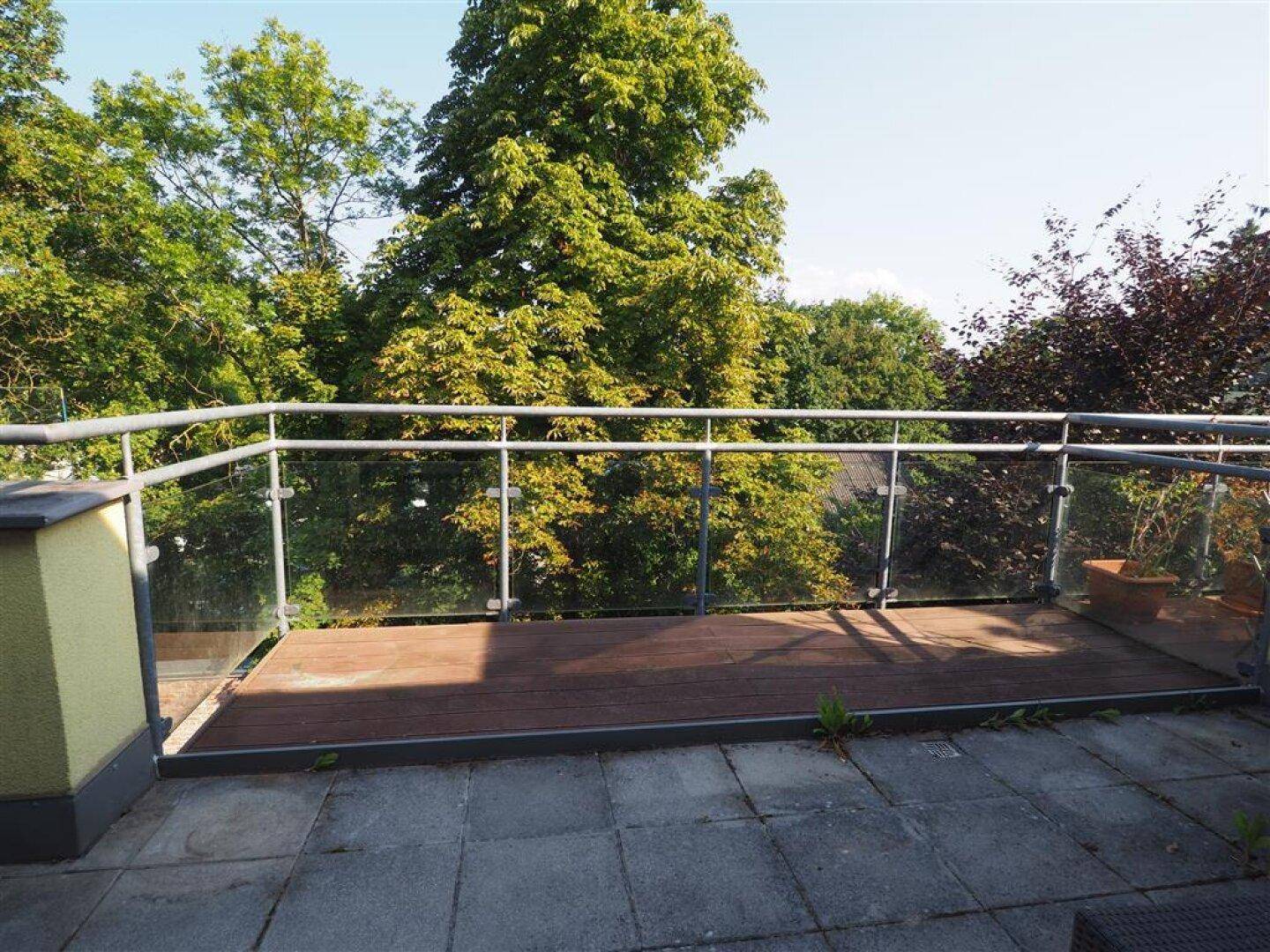 Weitläufige Dachterrasse mit Steinplatten und Holzdeck, ideal zum Entspannen im Freien.