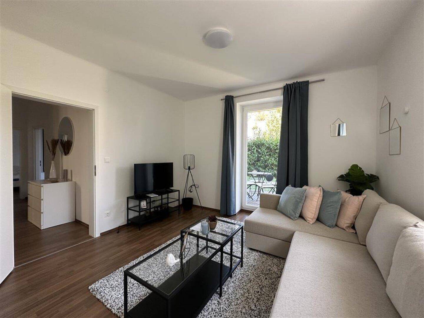 Wohnzimmer mit Sofa, Fernseher und Zugang zu einem Außenbereich, der zum Entspannen einlädt.