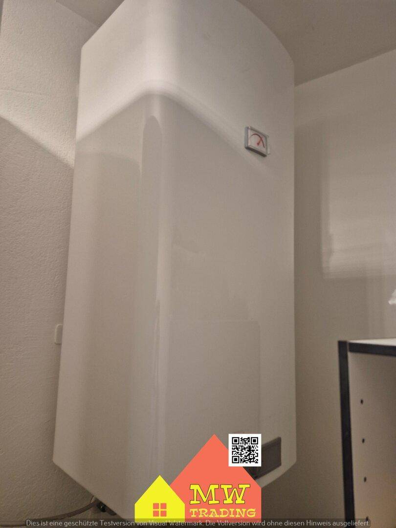 Großer weißer Warmwasserspeicher oder Boiler in einem Hauswirtschaftsraum.