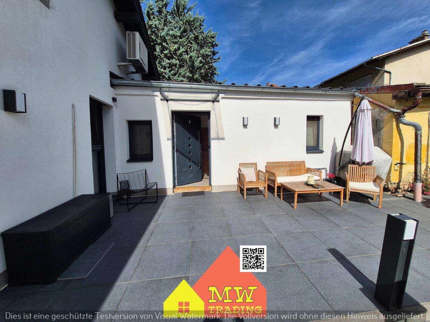 Eingangsbereich zur Terrasse mit modernen Fliesen und gemütlichen Holzmöbeln für entspannte Stunden.