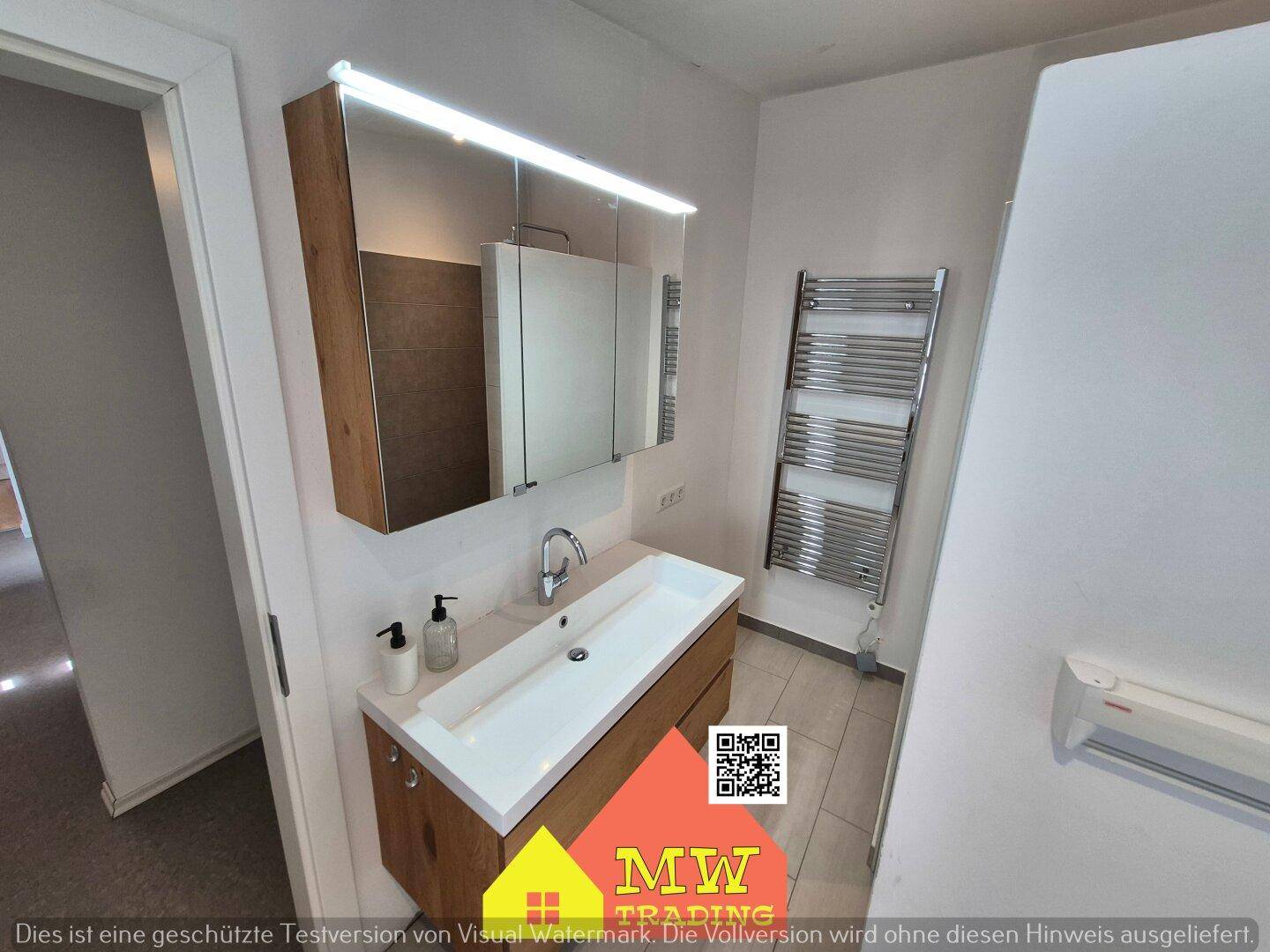 Badezimmer mit modernem Waschtisch, Spiegelschrank und beheiztem Handtuchhalter für Komfort.